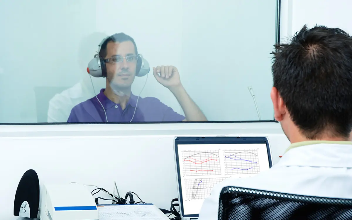 A man sitting in front of a window with headphones on.