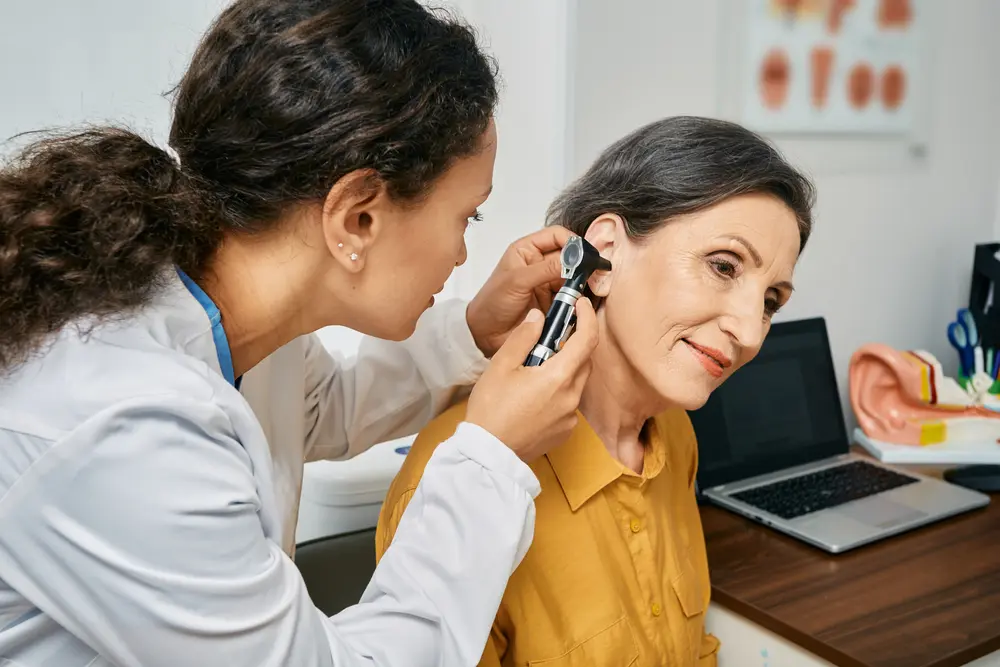 A woman is getting her ear checked by an audiologist.