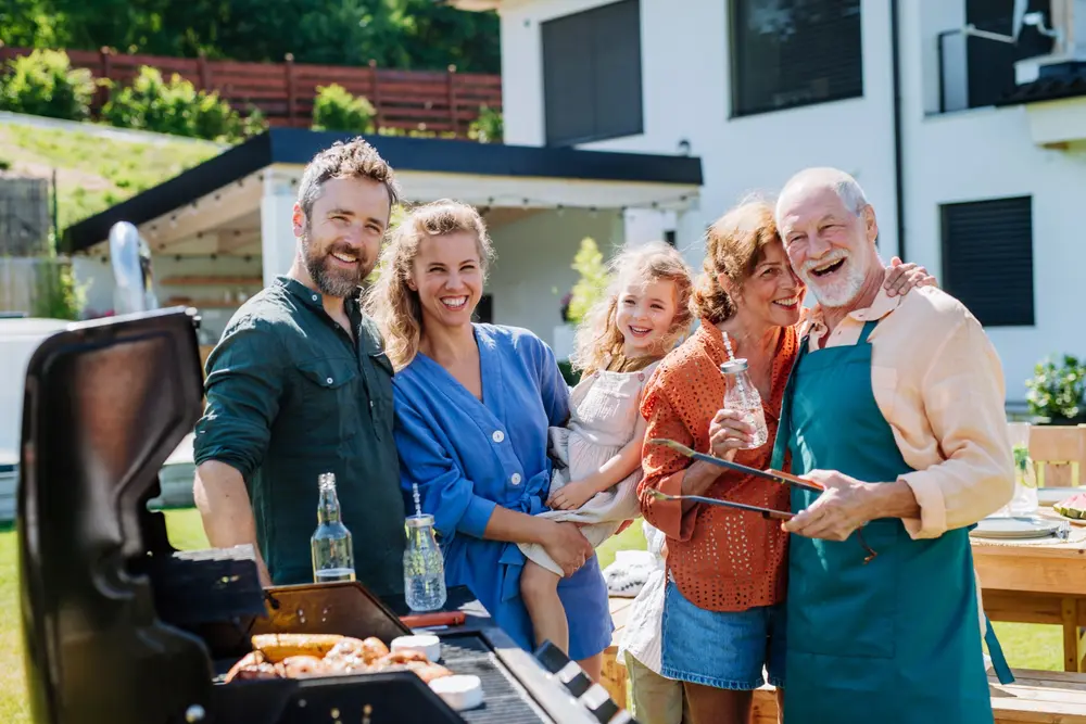 A group of people standing around an outdoor grill.