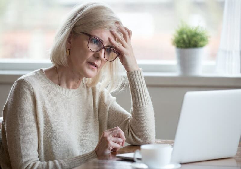 A woman sitting at a table with her hand on the forehead.