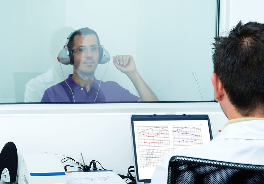 A man sitting in front of a window with headphones on.