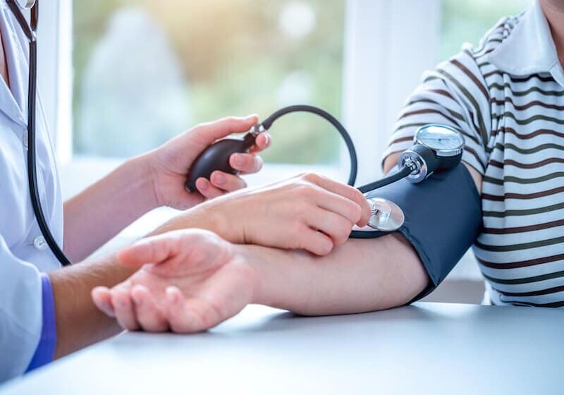 A person is taking blood pressure from another person.