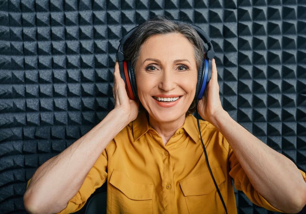 A woman wearing headphones and smiling for the camera.