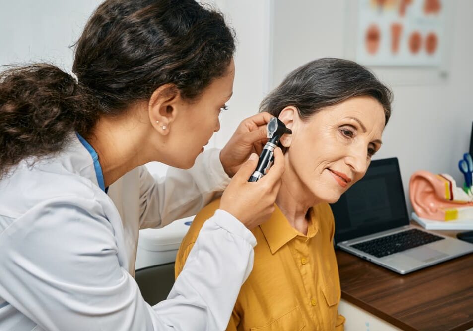 A woman is getting her ear checked by an audiologist.