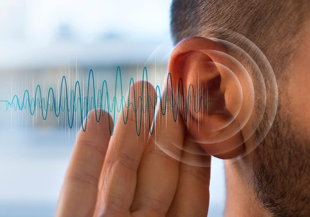 A person with their ear being heard by an audio wave.