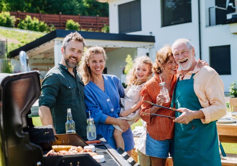 A group of people standing around an outdoor grill.